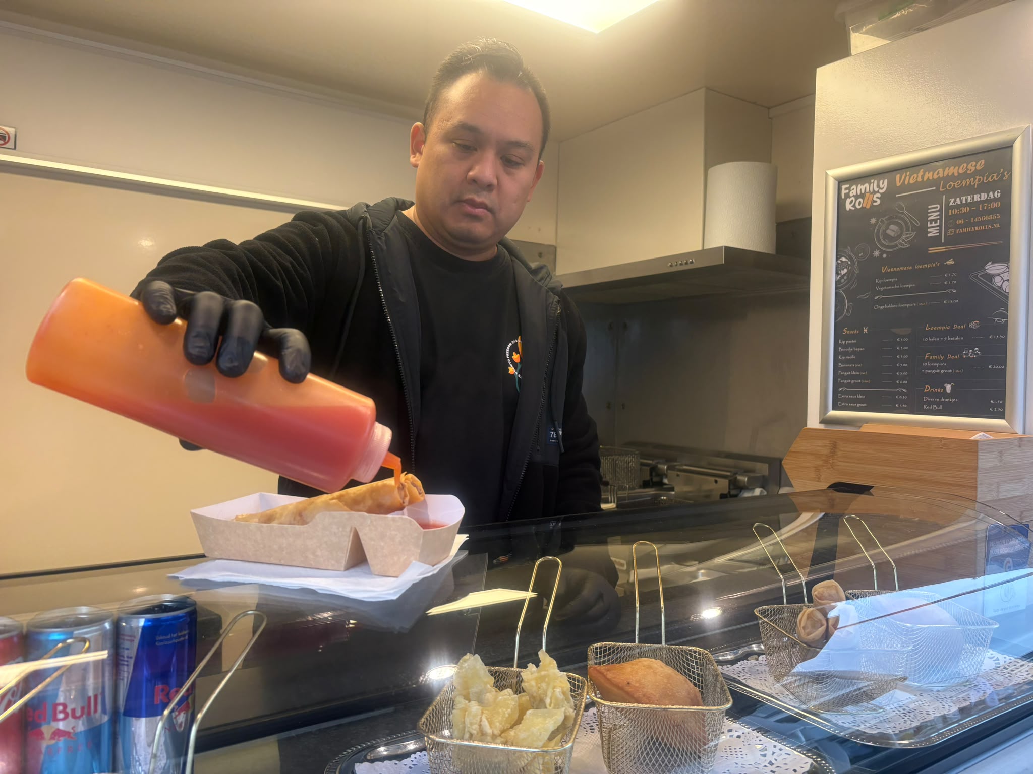 Ninh schenkt saus over een verse loempia in de Family Rolls foodtruck
